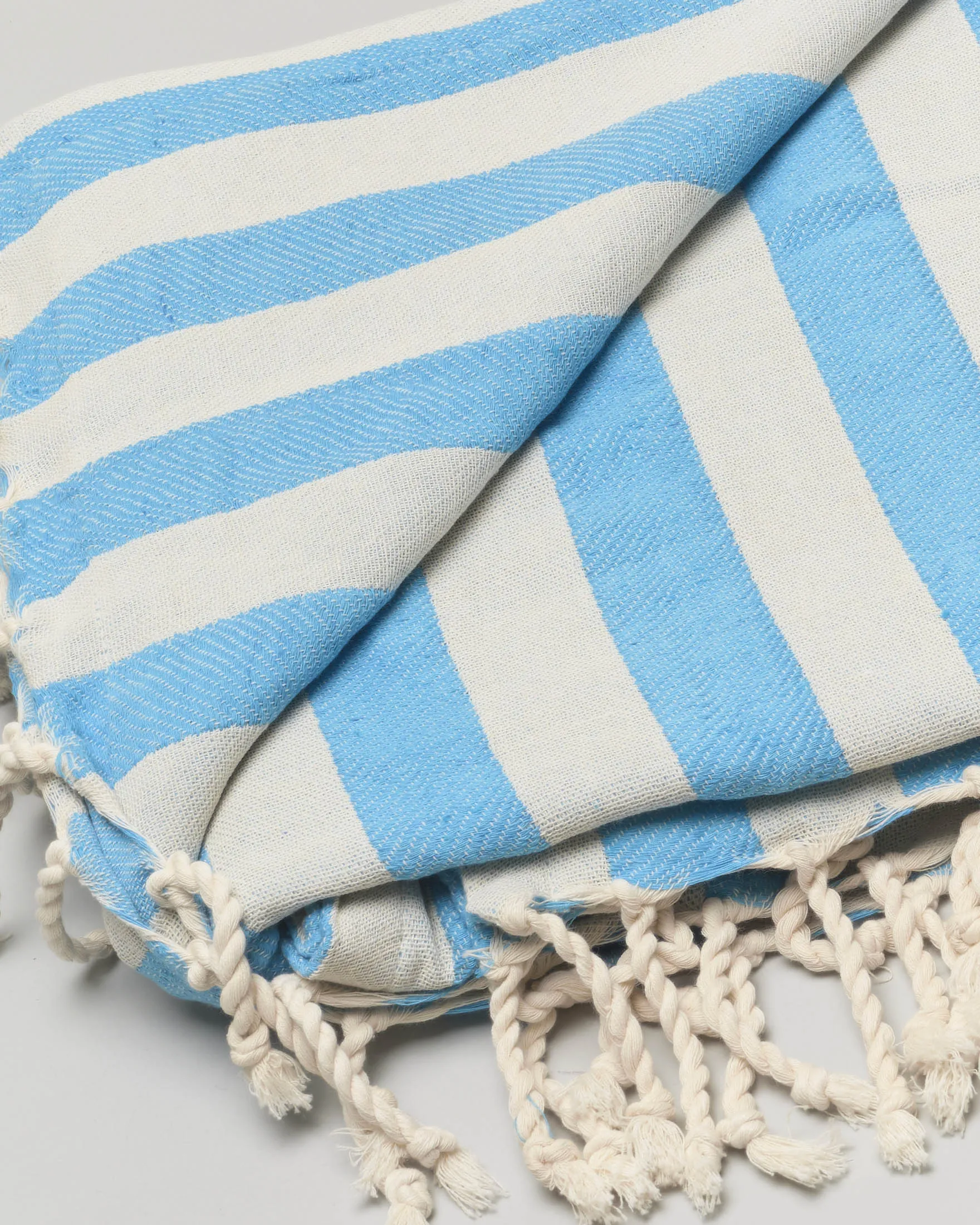 Telo mare in cotone a righe bluette e bianche con frange al fondo e scritta logo ricamata